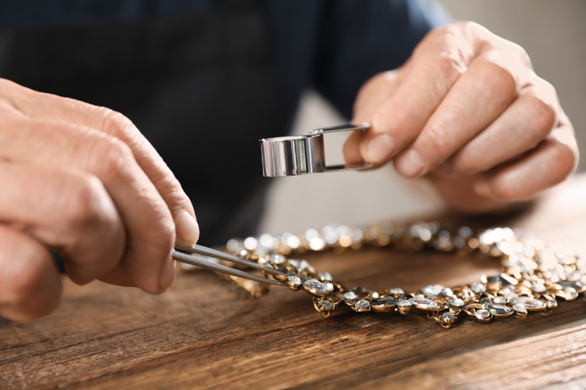 man with appraisal tools evaluating a vintage diamond necklaces