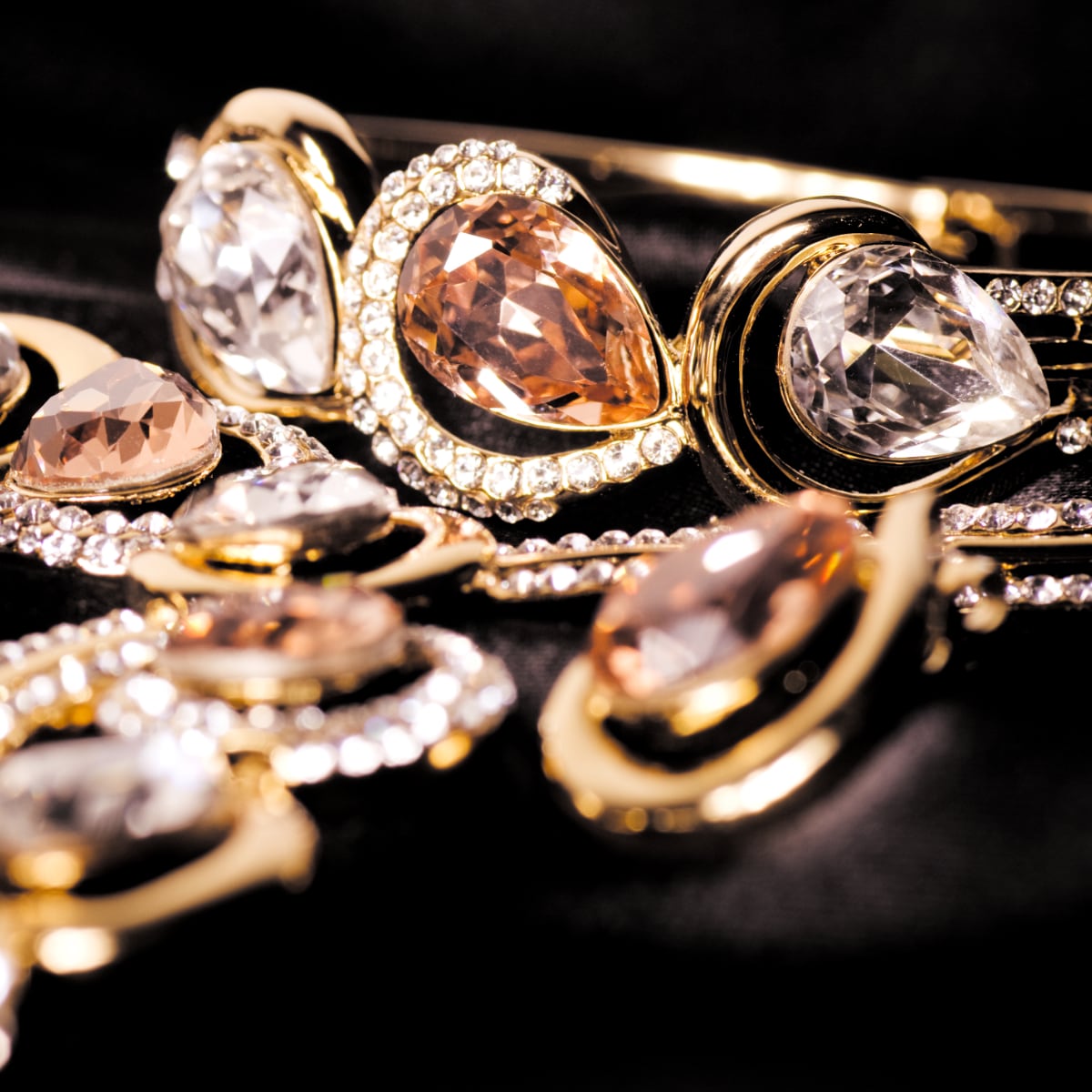 Collection of diamond and gem gold jewelry on black background.